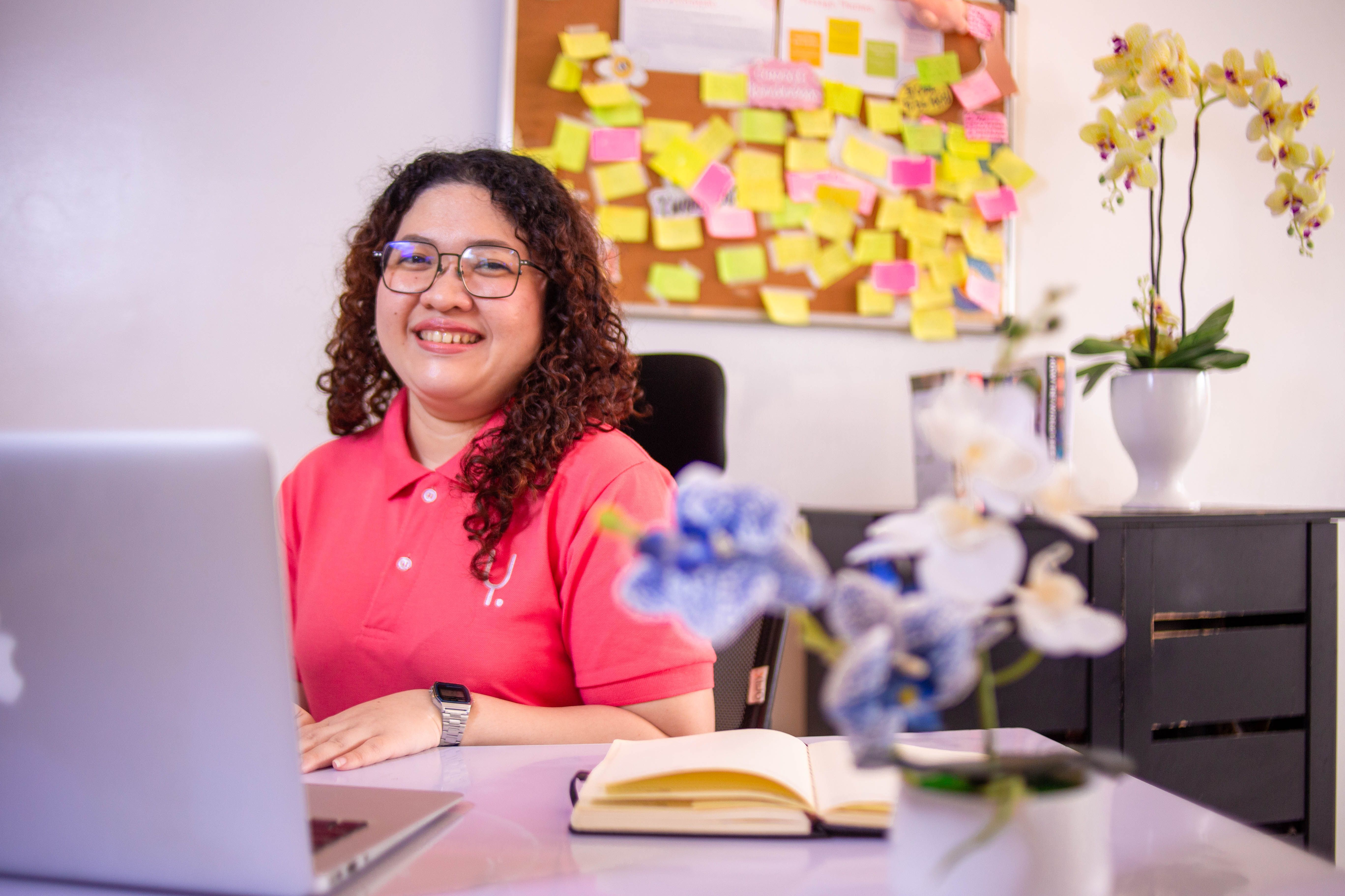 Yoonet bookkeeper smiling at her desk with a laptop and notebook