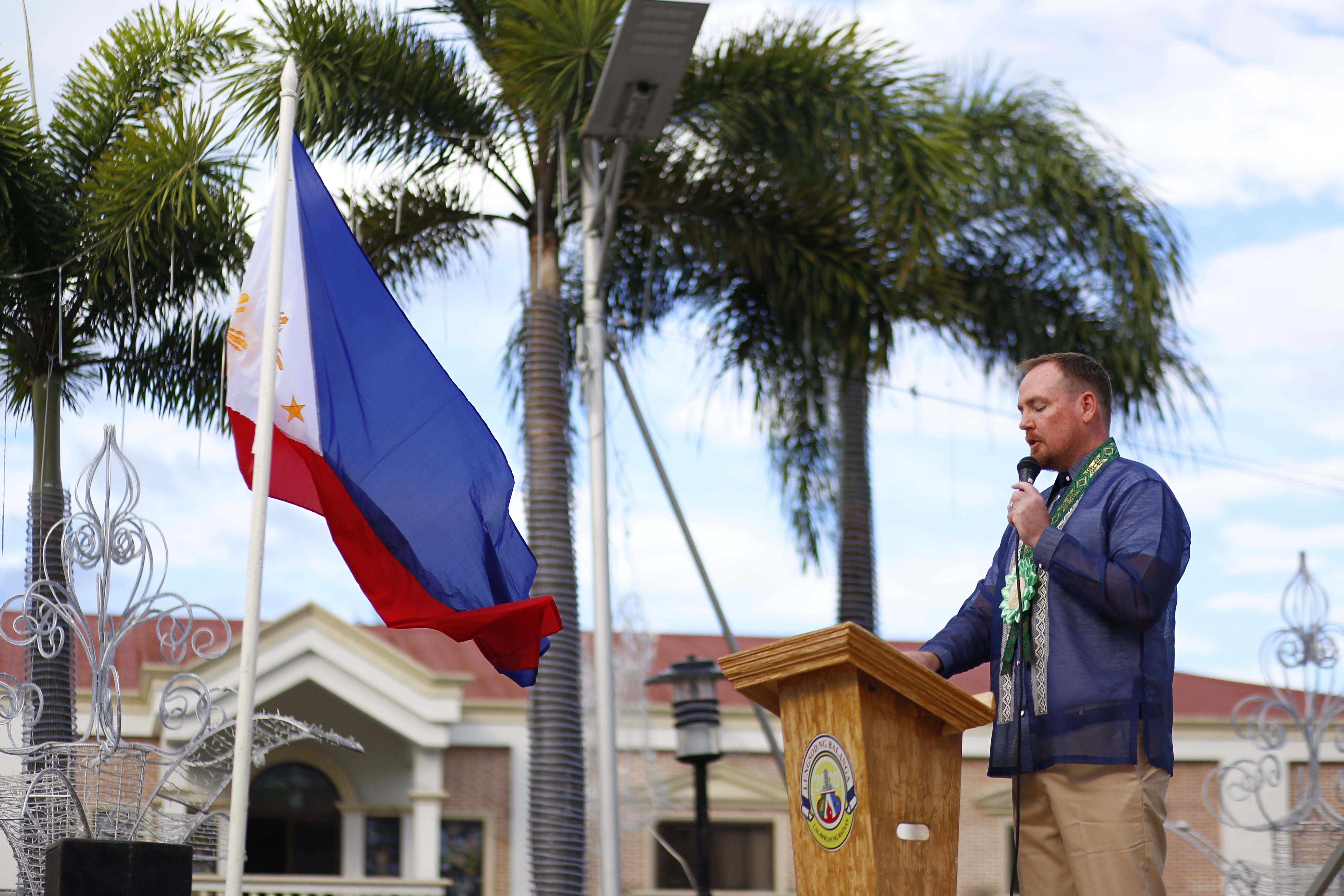 Yoonet founder Ben Carter speaking at the Balanga City podium beside the Philippine flag