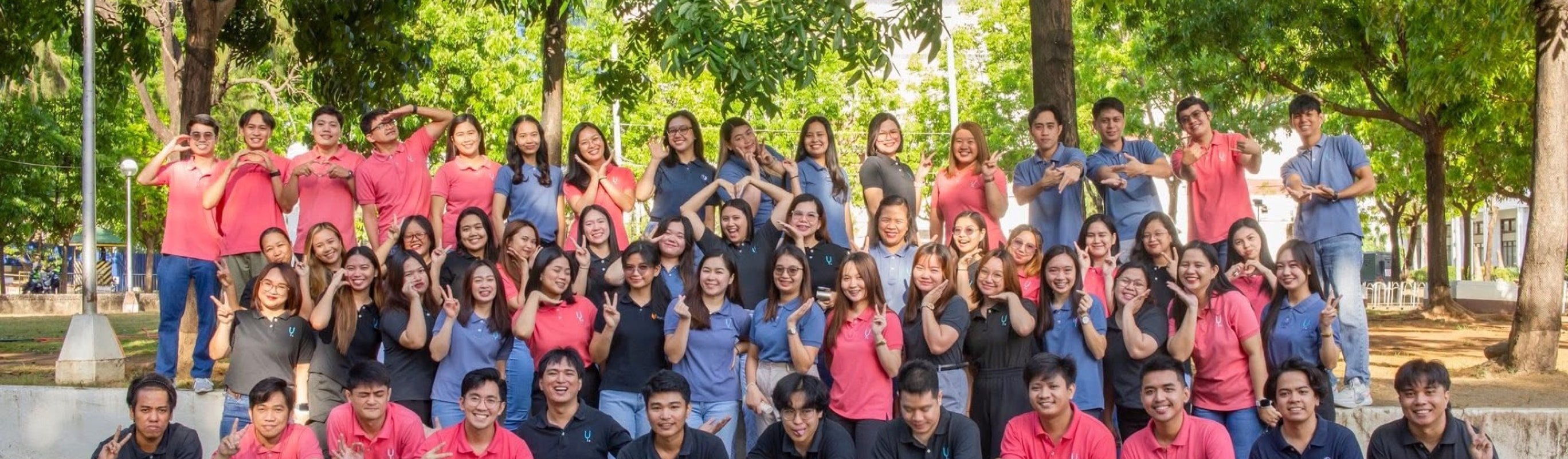 The whole Yoonet team laughing and throwing peace signs under the trees in Balanga City