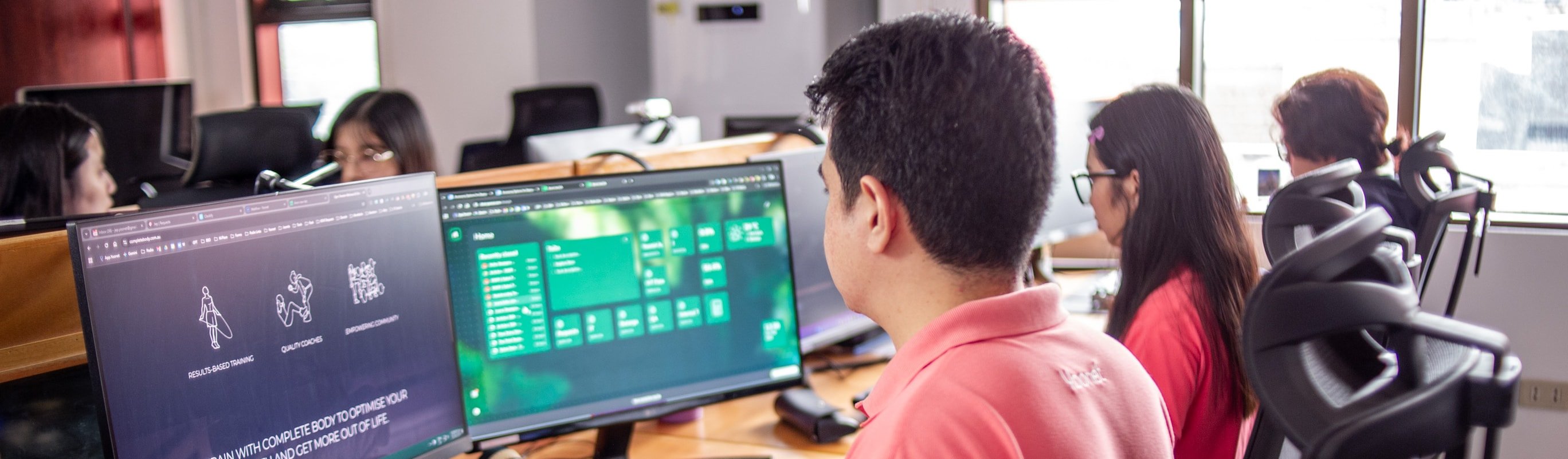 Yoonet digital team developers at dual-monitor workstations in the Balanga office, working on a client website