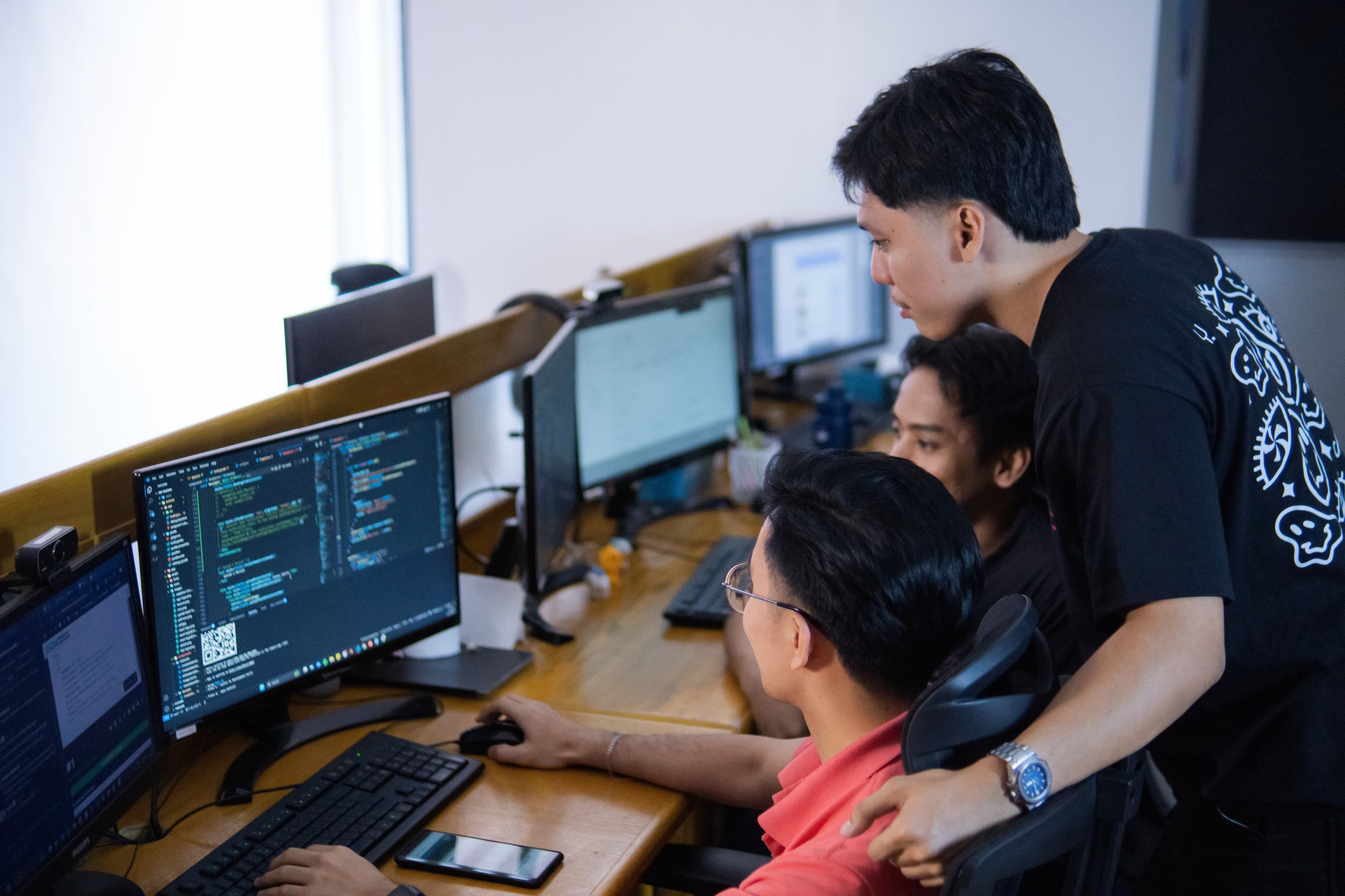 Yoonet digital teammates reviewing code together at a multi-monitor workstation