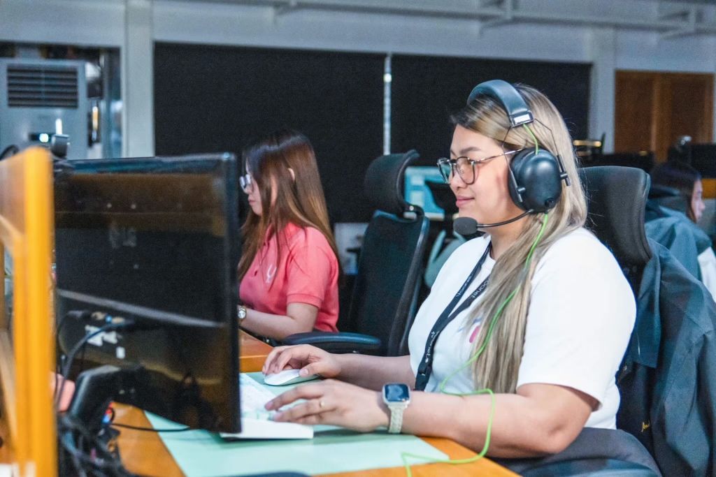 A row of Yoonet team members at their workstations in the Balanga office, the teammate in focus wearing a headset as she works at her monitor