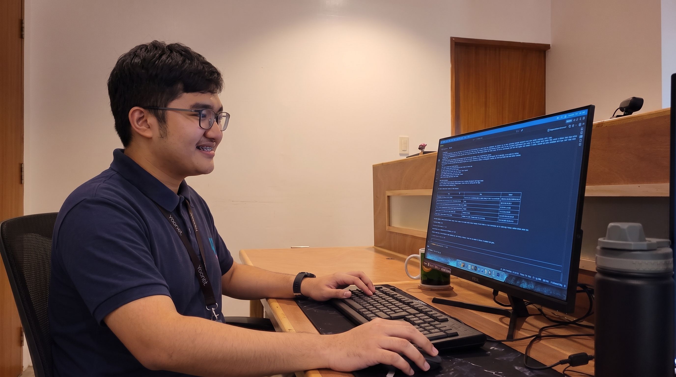 Yoonet practice admin teammate smiling while working on patient records at a dual-monitor workstation in the Balanga office
