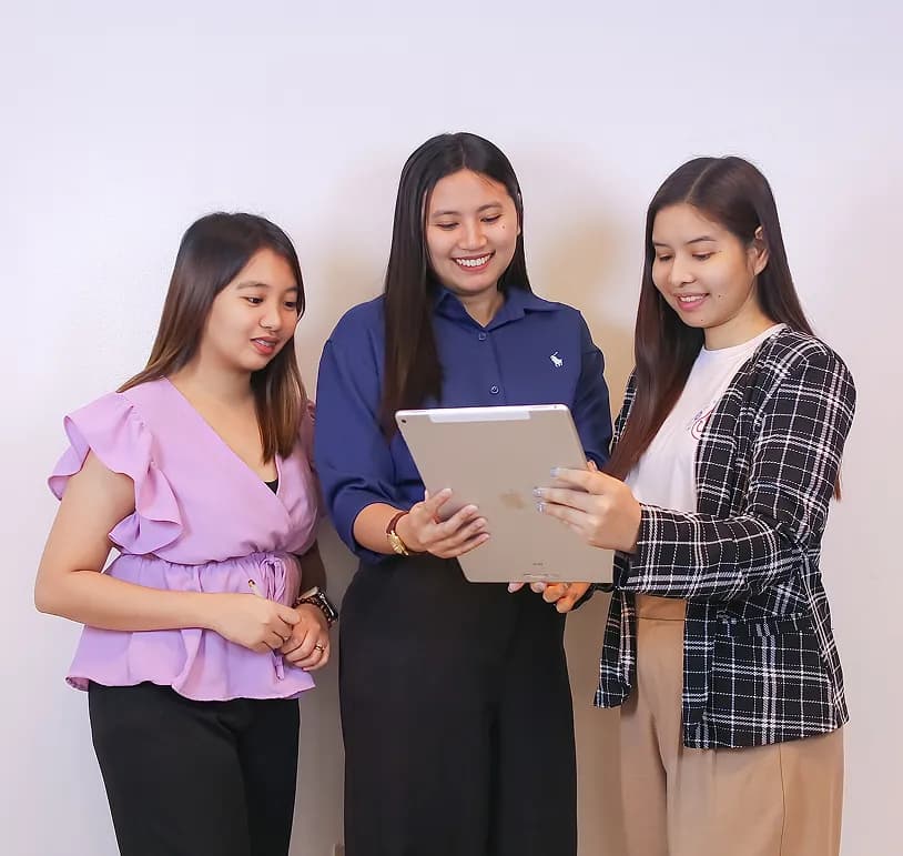 Yoonet team members looking at a tablet together and smiling